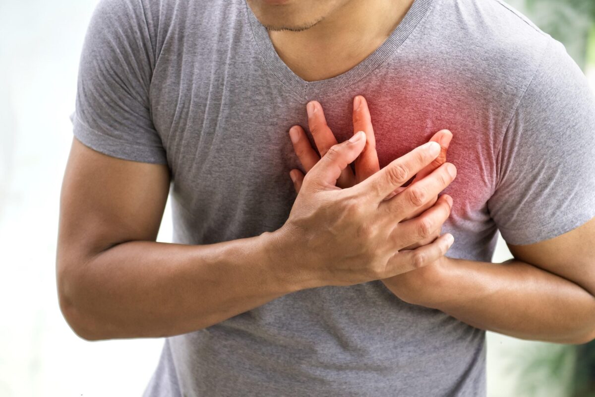 Person experiencing chest pain holding their chest, illustrating heart-related causes of chest pain that require emergency care