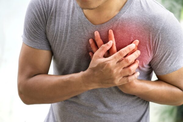 Person experiencing chest pain holding their chest, illustrating heart-related causes of chest pain that require emergency care