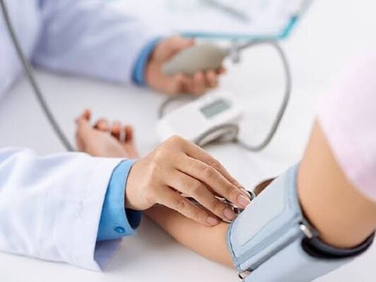blood pressure monitoring diabetes — patient using home blood pressure cuff with digital reading showing hypertension in diabetes management