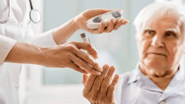 older adult checking blood glucose level with a glucometer at home as part of diabetes self-management