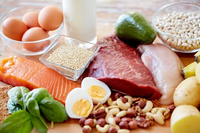 Foods that help lower cholesterol — oats nuts legumes olive oil and fish on a wooden table