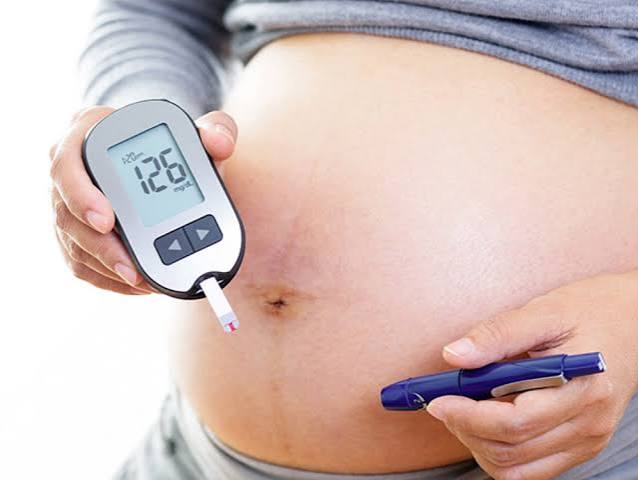 pregnant woman checking blood glucose at home as part of gestational diabetes management plan