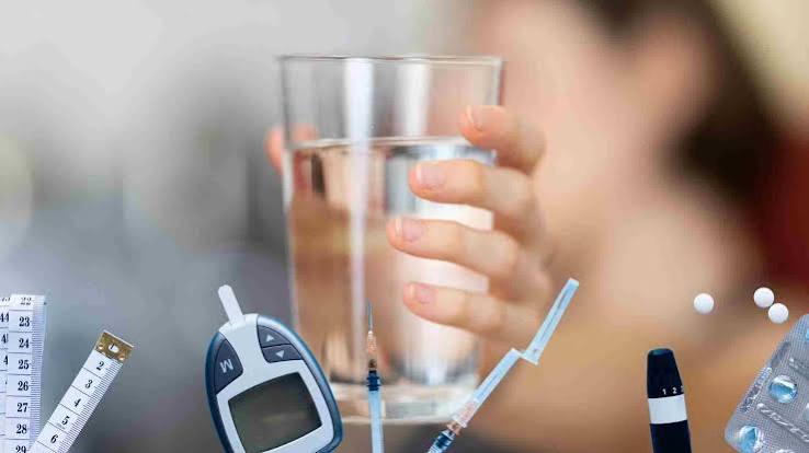 hydration and blood sugar — glass of water next to glucose meter showing connection between fluid intake and glucose