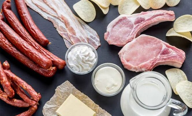 Saturated fat and cholesterol — butter, red meat, and cheese on a wooden board