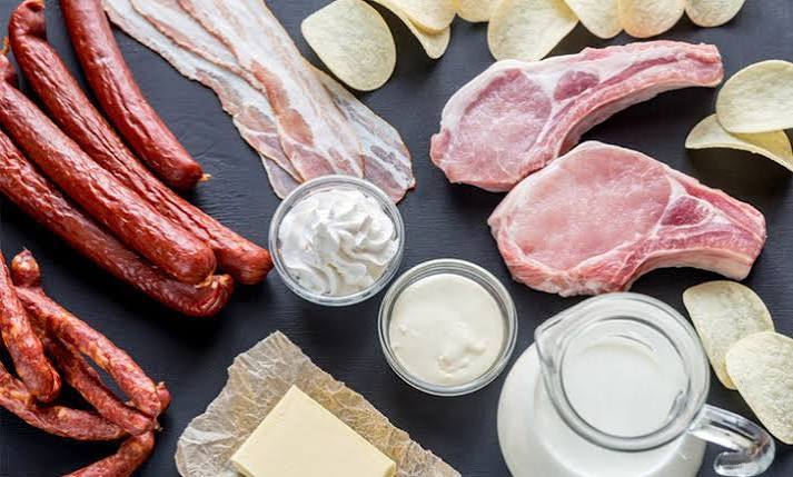 Saturated fat and cholesterol — butter, red meat, and cheese on a wooden board
