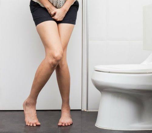 Difficulty starting urination — man experiencing urinary hesitancy at restroom illustrating the common symptom of delayed void initiation from BPH and other causes