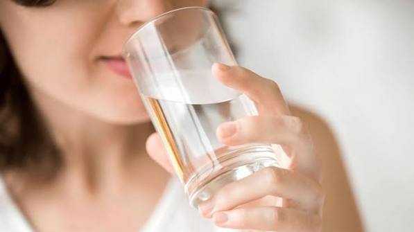 hydration and kidney stone prevention — person drinking water from a glass showing adequate daily fluid intake strategy for preventing kidney stone formation
