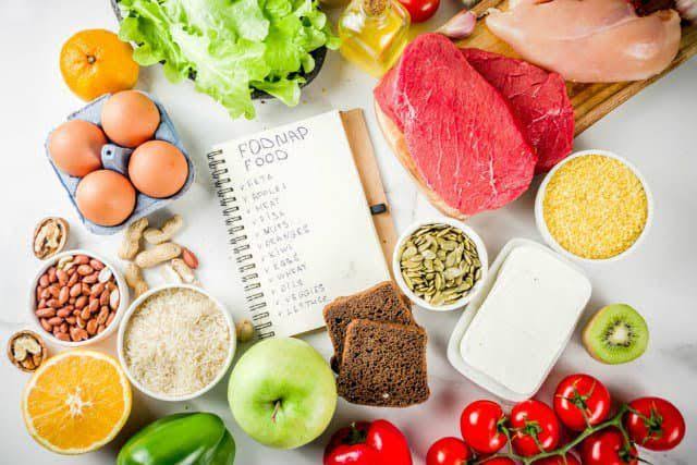 Low-FODMAP foods for IBS including rice, oats, carrots, eggs, lean meat and lactose-free dairy alongside high-FODMAP foods to avoid including wheat, garlic, onion, apples and legumes