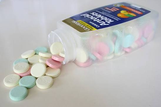Adult reading antacid medication packaging label showing calcium carbonate antacids used for heartburn and acid indigestion relief