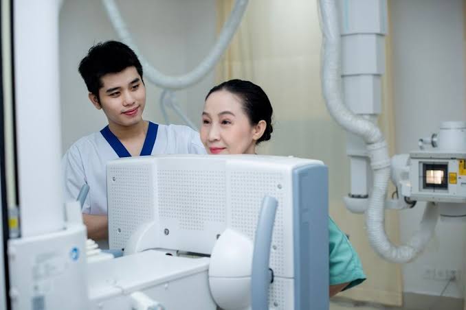 DEXA scan machine showing a large open gantry with a flat examination table and a movable arm above it used for measuring bone mineral density at the hip and lumbar spine in a clinical radiology setting