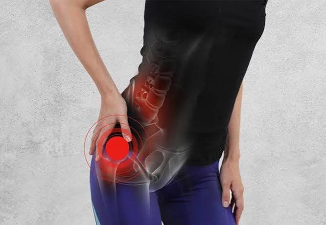 Sciatica symptoms and causes — adult holding lower back and leg showing radiating sciatic nerve pain from lumbar disc herniation