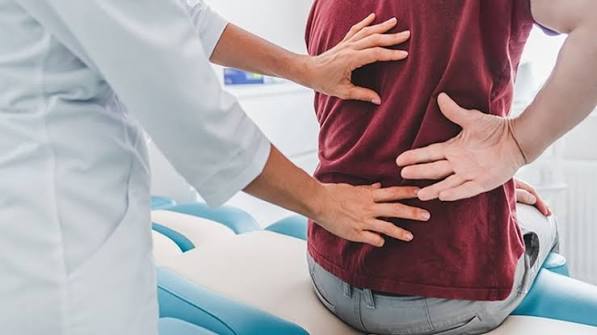 When back pain needs medical attention — illustration of a lumbar spine showing cauda equina nerve roots, vertebral metastasis, and inflammatory sacroiliitis, representing the red flag back pain conditions requiring urgent assessment
