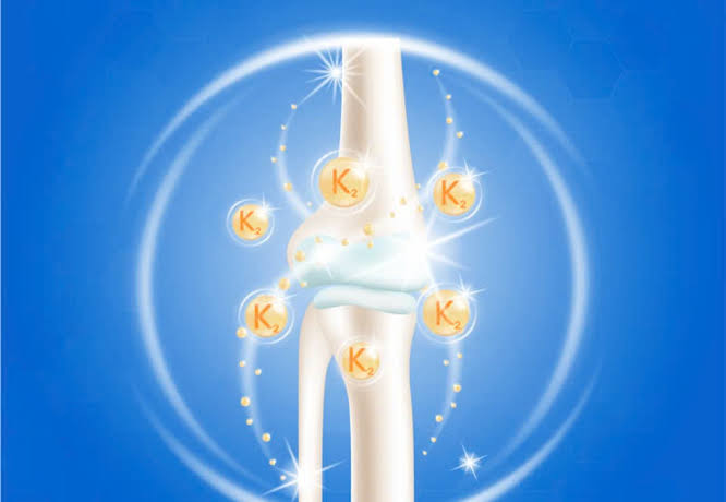 Vitamin K and bone health diagram showing vitamin K1 from green leafy vegetables and vitamin K2 from fermented foods and cheese as dietary sources alongside the carboxylation mechanism activating osteocalcin and matrix Gla protein for bone mineralisation and vascular protection
